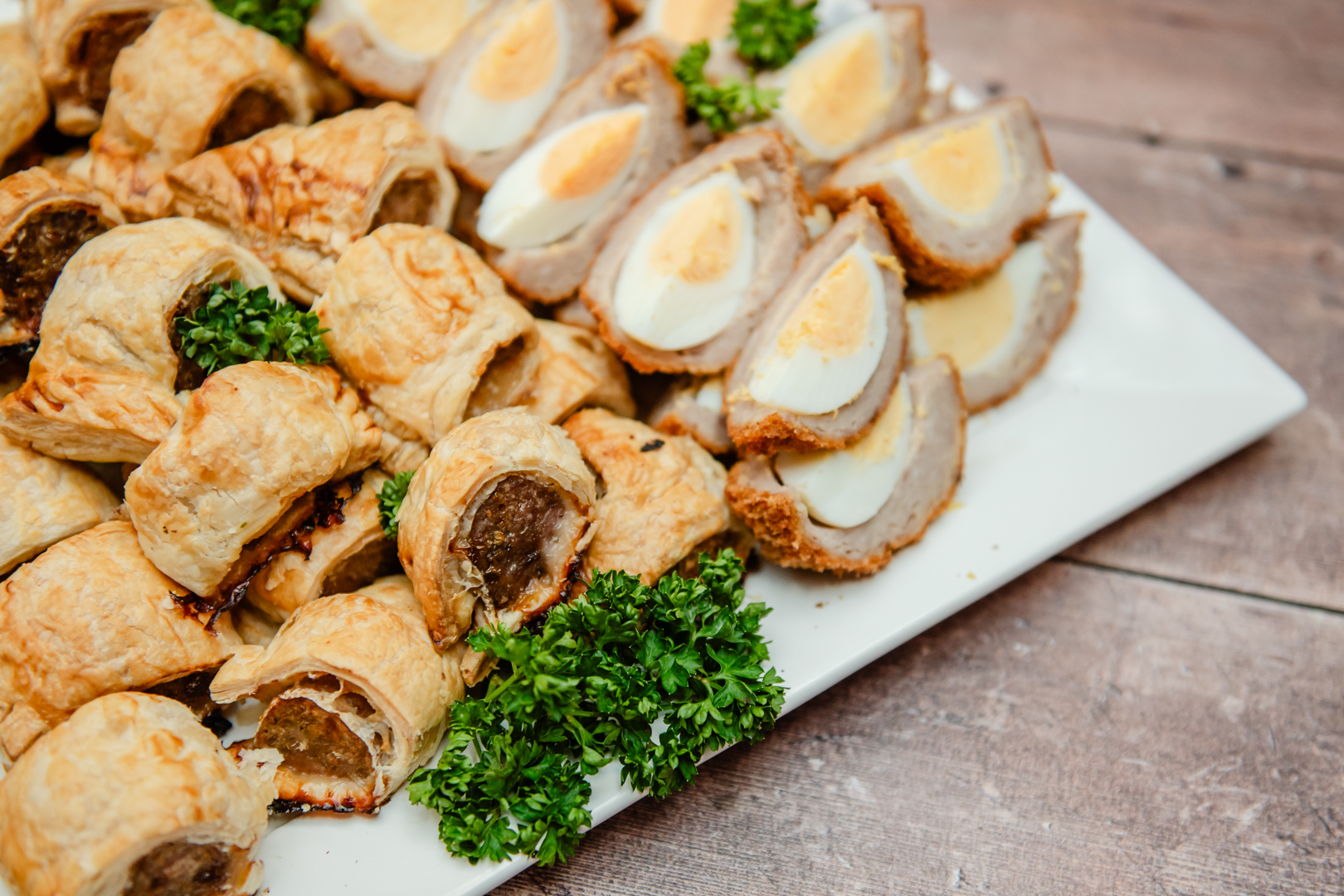 sausage rolls and scotch eggs on a white plate catering by Saxtons deli Church Stretton